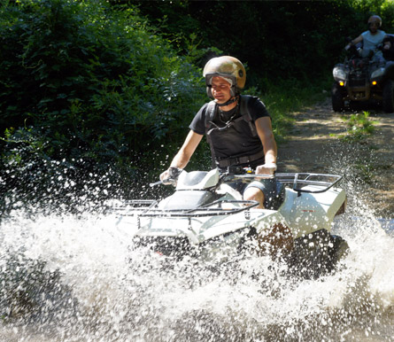 Un randonneur en quad traverse un cour d'eau